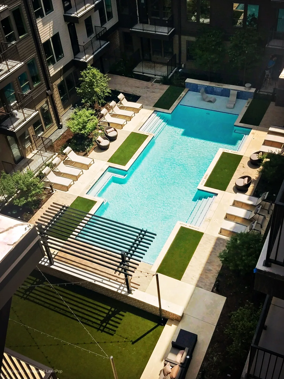 Aerial view of an apartment pool courtyard with artificial turf