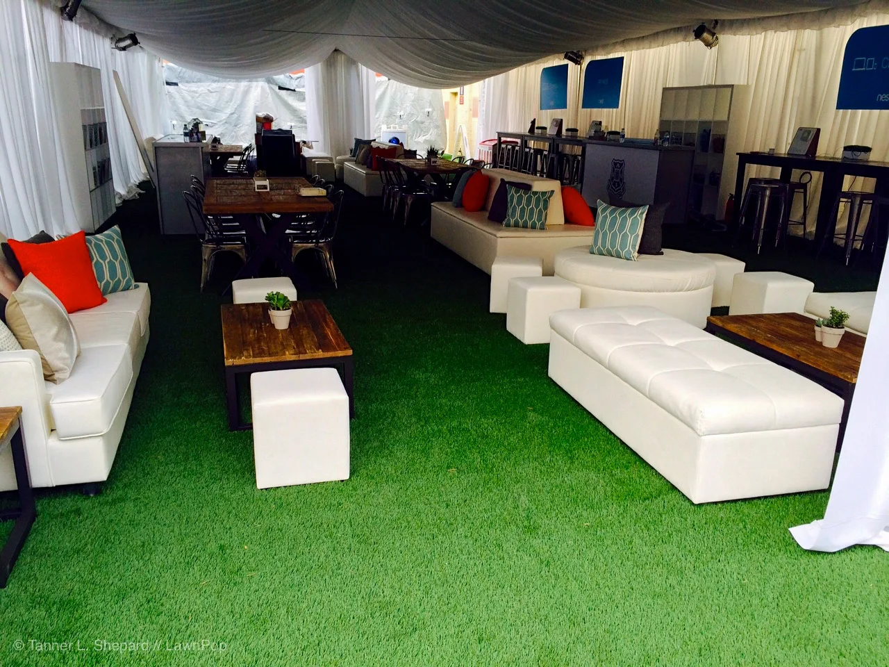 White event lounge furniture on artificial turf beneath a tent