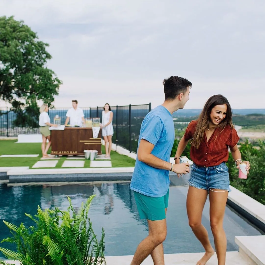 Couple walking beside a pool bordered by artificial turf