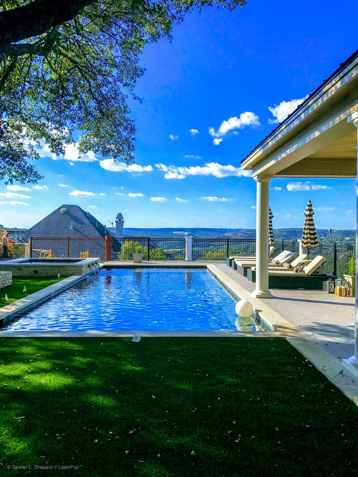 Resort-style pool framed by artificial turf and a pergola