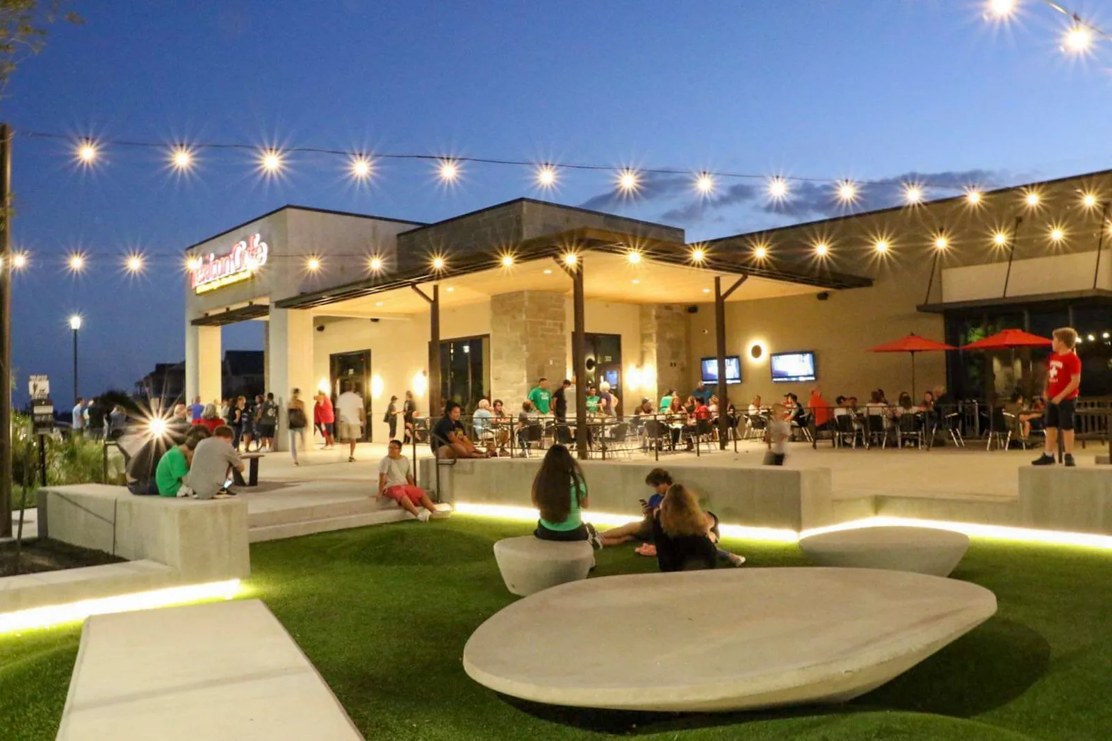 Restaurant patio with string lights and artificial turf at dusk