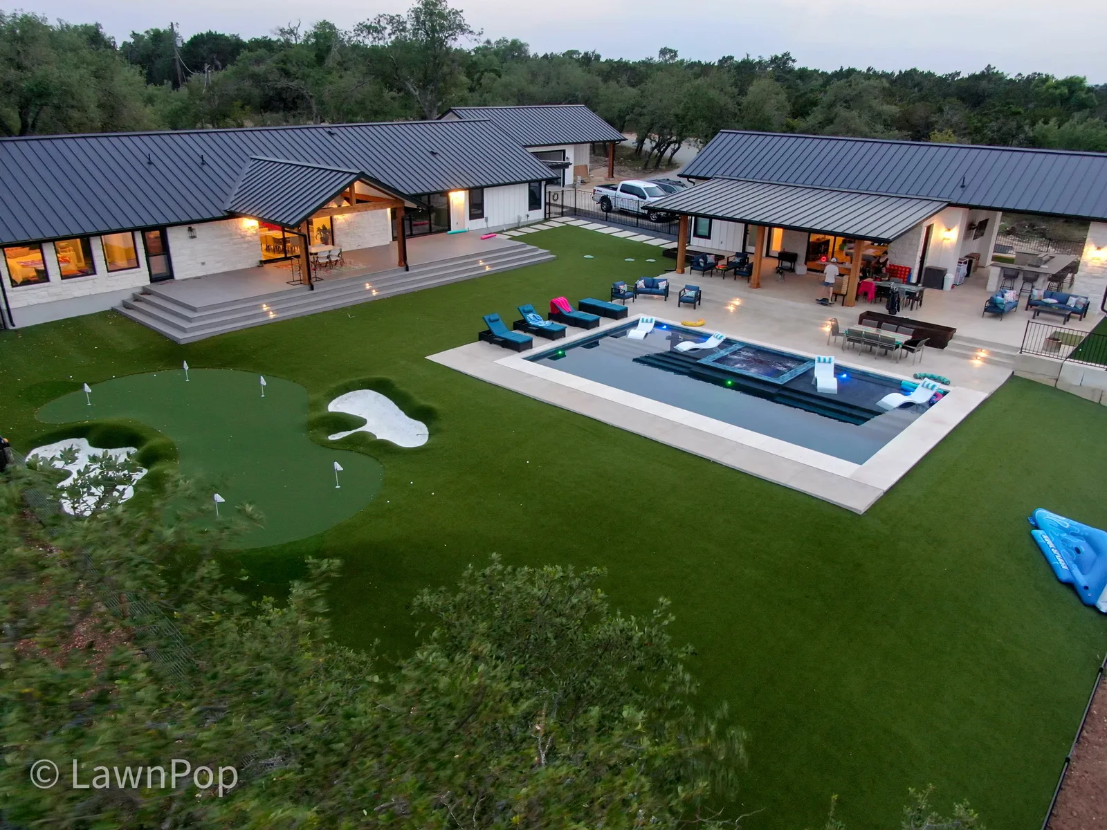 Aerial view of a custom multi-hole putting green with bunkers beside a pool in the Texas Hill Country