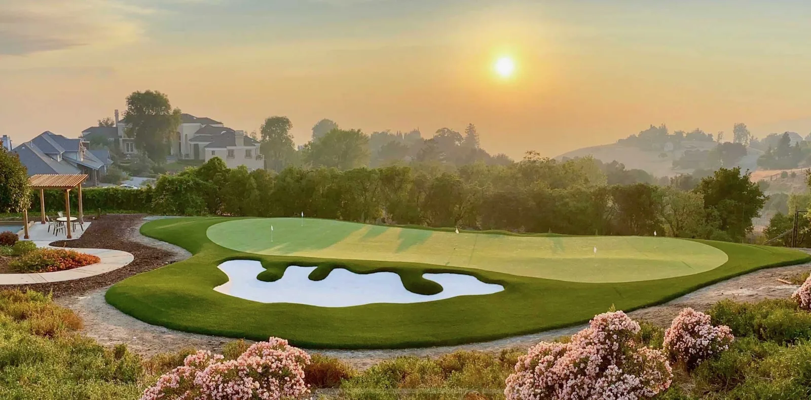 Luxury golf green with sculpted white bunkers at sunrise
