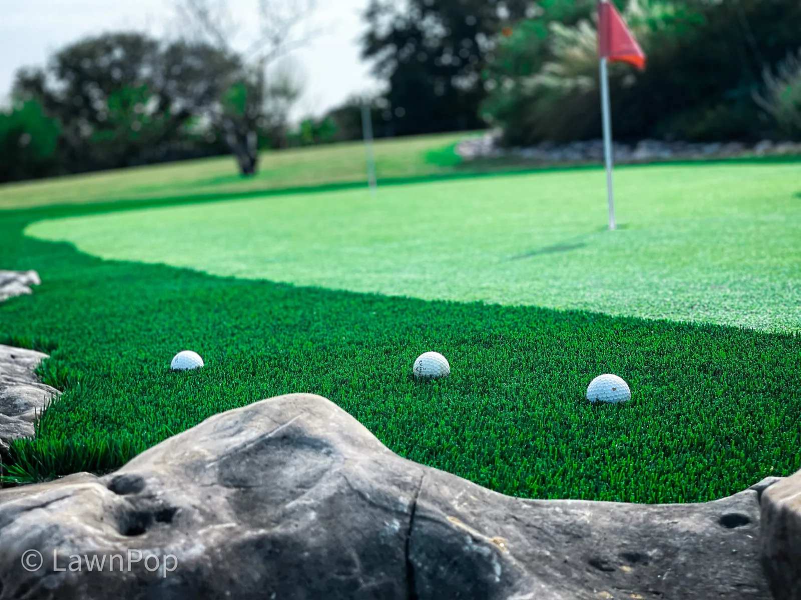 Golf balls rolling toward the cup on a LawnPop synthetic putting green