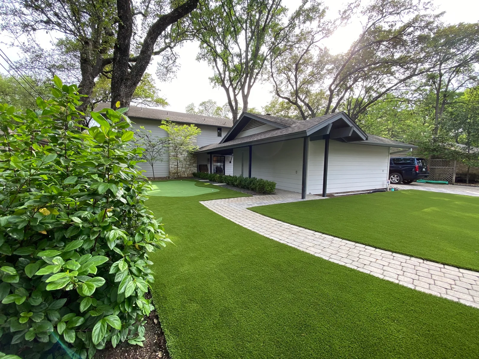 Front-yard artificial turf with a paver walkway and manicured beds
