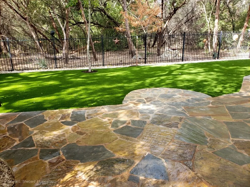 Artificial turf lawn bordered by a flagstone patio