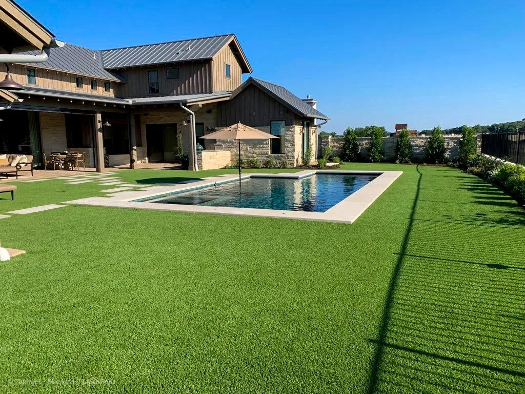 Modern home with a pool and a wide artificial turf lawn