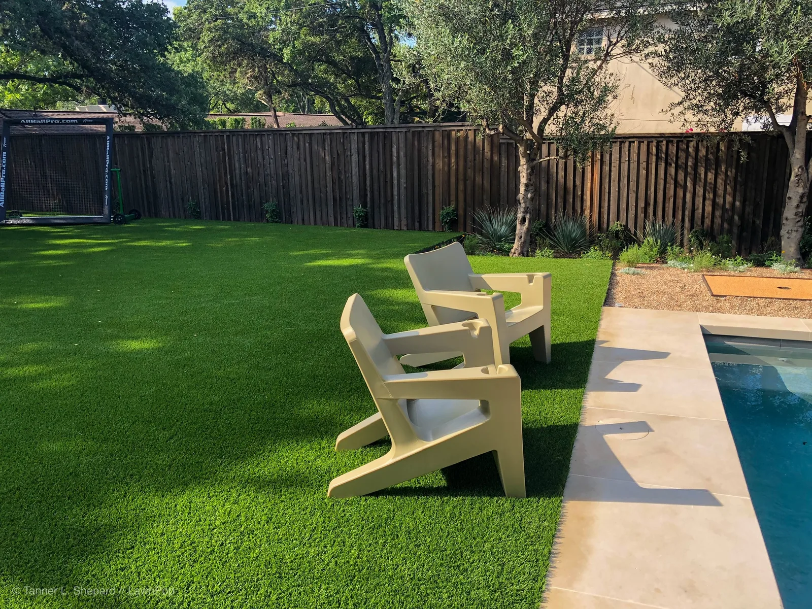 Backyard artificial lawn with lounge chairs beside a pool